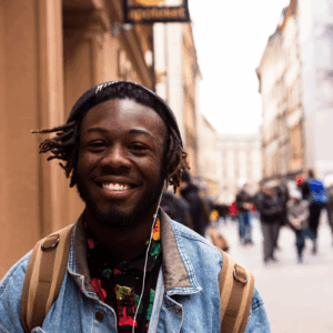 Glad ung kille som går på gatan och lyssnar på musik i hörlurar.
